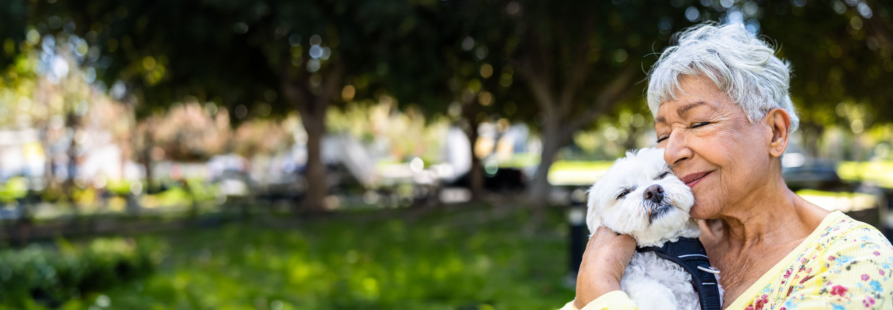 Woman holding dog to face with eyes closed