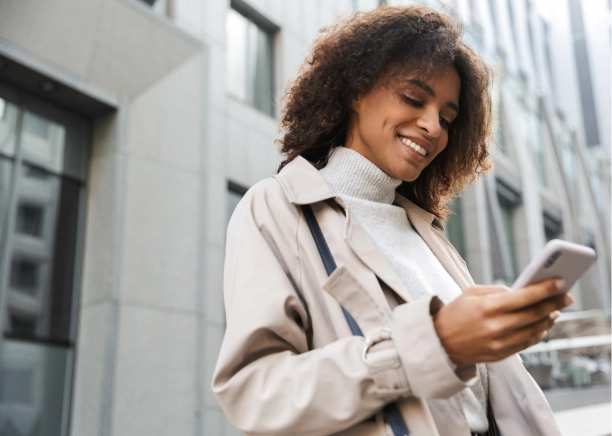 Woman smiling down at her phone outside